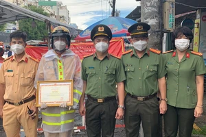 Đại tá Hoàng Văn Hà, Phó Cục trưởng Cục An ninh điều tra Bộ Công an (A09) trao tặng bằng khen cho Thiếu tá Lê Hoàng tại chốt kiểm soát phòng chống dịch. Ảnh: CHÍ THẠCH 