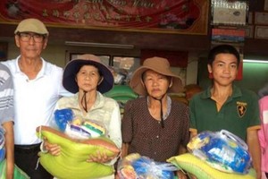 越僑姚保昌(左一)向貧戶贈送禮物。 
