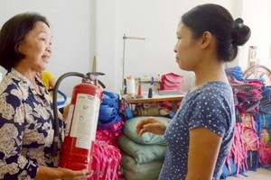 舊邑郡第十二坊第十三街坊組長裴氏慶指引民眾使用小型滅火器。