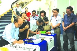 華人書畫家張路與李松年在寫書法作品。