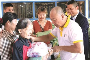 鄭成龍理事長向窮人派發禮物。