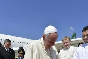 教宗方濟各昨天飛抵曼谷廊曼國際機場時，受到民眾熱烈歡迎，並與一名身穿少數族群傳統服裝的孩童擁抱。 （法新社）