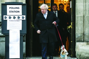 英國首相鮑里斯‧約翰遜在一個投票站投票後牽著他的小狗離開。