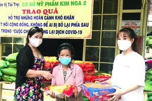 梁柳嬋(左一)與媳婦(右一)向窮人贈送禮物。