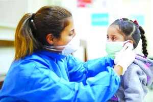 護士在疫情期間為一名女孩測量體溫。