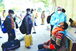 乘客在印度德里一處巴士終點站接受新冠病毒檢測取樣。