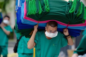 第二郡6號新冠肺炎野戰醫院醫護人員背著沉重的物資進入治療、隔離區。