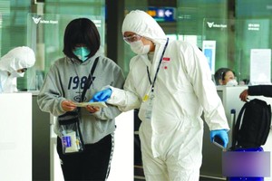 韓國仁川機場，航空公司工作人員檢查旅客防疫證明等。