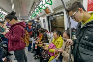 人们在乘坐地铁时低头玩手机。