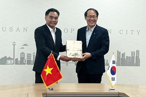 胡志明市人委会副主席阮禄河（左）向韩国釜山市副市长李俊承赠送纪念品。