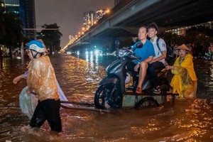 9月30日晚，河内市民使用载摩托车通过水淹路段服务。