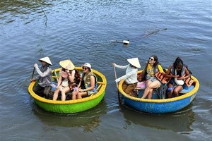 国际游客乘坐簸箕船穿越椰林。