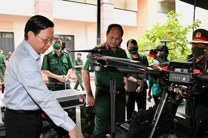 Chairman of HCMC People’s Committee Phan Van Mai is visiting the exhibit on combat weapons and assets in the meeting. (Photo: SGGP)