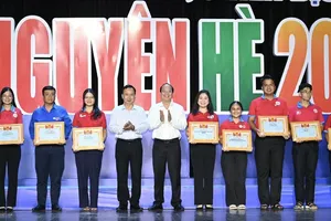 Deputy Head Nguyen Lam of the Central Committee for Mass Mobilization and Standing Deputy Secretary Nguyen Ho Hai of the HCMC Party Committee are commending outstanding collectives and individuals (Photo: SGGP) 