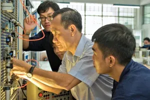 A lecturer of the Faculty of Electrical and Electronic Engineering (HCMC University of Technology – HCMUT) is teaching their students in a practice workshop 