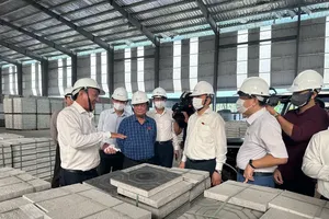 Deputy Chairman of the National Assembly Le Minh Hoan (second from left) and the supervision delegation listen as BIWASE leaders explain the process of producing recycled bricks from waste on July 24