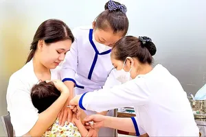A medical worker at a vaccination center in HCMC is administering a vaccine to a child to protect against infectious diseases