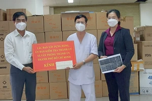 Phó Trưởng Ban Dân vận Thành ủy Ngô Văn Luận (bìa trái) trao bảng tượng trưng hỗ trợ y bác sĩ, nhân viên y tế Bệnh viện dã chiến thu dung điều trị Covid-19 số 2. Ảnh: HOÀI NAM