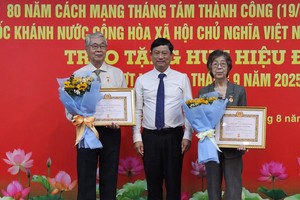 胡志明市委副书记、市人民议会主席武文明向华人刘金华（右）颁发60年党龄纪念章。