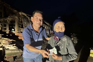 长虹旅游公司主理人温越强(左）捐助现金给当地贫困老人家。