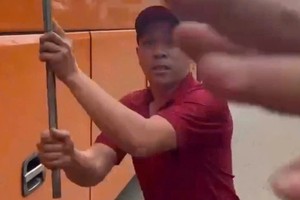 一名身穿客运公司制服的男子下车，拿出一根约1米长的铁棍，恐吓并企图殴打从后方驶来的摩托车驾驶者。