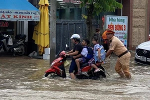 Một học sinh phụ giúp đẩy xe vượt qua triều cường