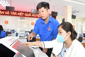 Đoàn viên thanh niên hướng dẫn người dân tra cứu dịch vụ công trực tuyến. Ảnh: VIỆT DŨNG