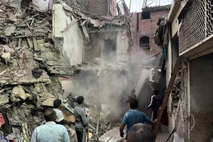 12月25日，救援人员在埃及吉萨省因巴拜区一处倒塌的房屋废墟工作。