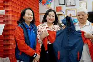 Phó Tổng Biên tập Báo SGGP Bùi Thị Hồng Sương tiếp nhận áo ấm do bà Nguyễn Thị Dậu, chủ cơ sở Như Lan, trao tặng. Ảnh: VIỆT NGA