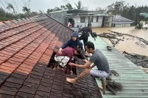 Người dân phải thoát qua mái nhà khi lũ dâng cao. Ảnh: TTXVN