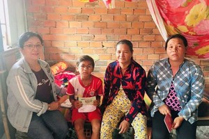 　　何飛燕（左一）搭了8個小時的車程向一少數 民族小朋友轉交手術經費。