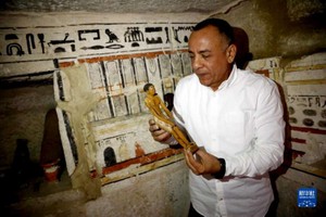 　　考古工作者在一處古墓內展示出土的一尊雕像。