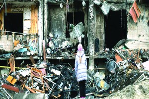 一名女孩看著一座公寓樓前爆炸留下的殘垣斷壁。