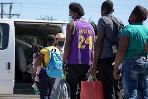 越過美墨邊境的移民在美國得克薩斯州德爾里奧等待上車。 新華社 圖