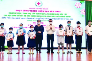 　　第六郡人委會主席黎氏青草與張豐裕先生向父母雙亡的孤兒派發禮物。