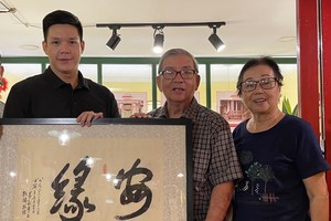 華人書畫家黃獻平（中）給鄧國長（左）贈送墨寶。