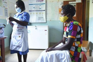 在烏干達卡巴萊的一家醫療中心，一名護士準備為一名患者接種新冠疫苗。