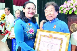 市人民議會主席阮氏麗向李金梅黨員頒發55年黨齡紀念章。