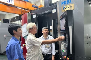 第七郡立福有限责任公司总经理阮文智指引工人操作机器。