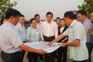 市交通工程投建管委会主任梁明福（中间白衬衫）和市人民议会主席阮氏丽（花衫）视察环市三路项目开展工作。