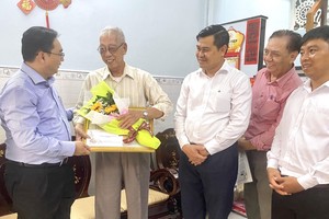 第十一郡该郡人委会主席阮陈平(左一)向华人何云贺寿。