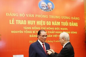 党中央总书记阮富仲向农德孟同志别上纪念章。