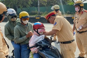 交警给一名孩子赠送并戴上安全帽。