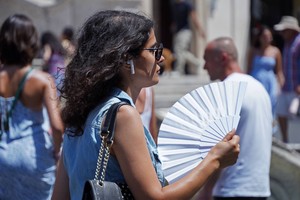 一名女子在意大利罗马街头扇扇子降温。(新华社)