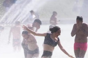 人们在喷泉里消暑纳凉。(新华社)