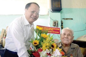 Deputy Standing Secretary of the Ho Chi Minh City Party Committee Tat Thanh Cang presents the 70-year Party membership badge to Party member Ly Toan Anh. (Photo: Sggp)