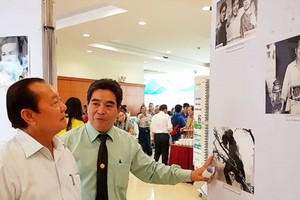 Former Secretary of the municipal Party Committee Le Thanh Hai (L) enjoys pictures in the exhibition. (Photo: Sggp)