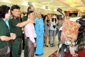 Painter Dang Ai Viet (Blue Ao Dai) presents to visitors her motorbike that she rode it to various parts of the country. (Photo: Sggp)