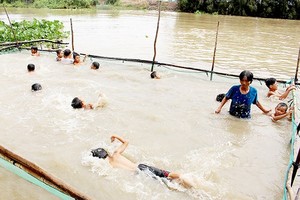 Mrs. Tran Thi Kim Thia is coaching kids in swimming.