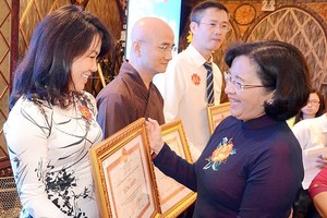 Ms.Than Thi Thu, Head of the Department of Propaganda & Education of HCMC Party Committee (R ) offers certificates of merit to individuals and organizations at the ceremony. (Photo: Sggp)